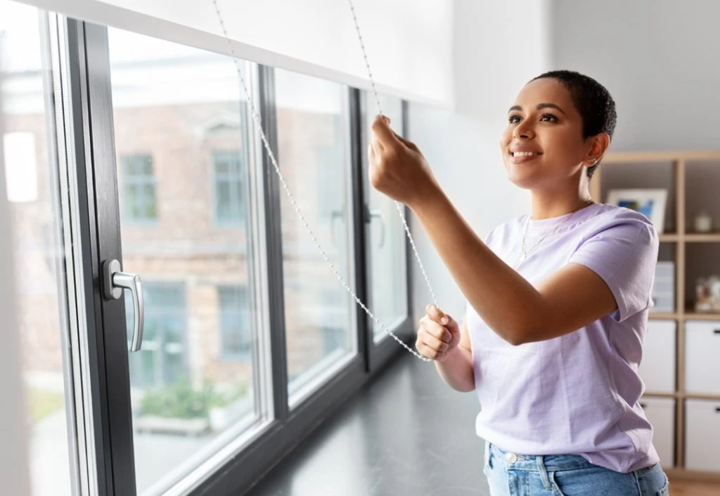 Person adjusting blinds on window