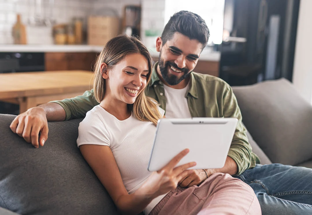man and woman at home looking at tablet
